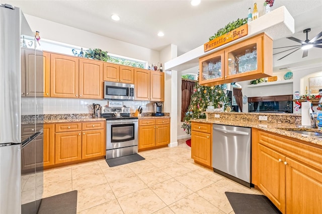 kitchen featuring ceiling fan, sink, tasteful backsplash, light stone counters, and appliances with stainless steel finishes