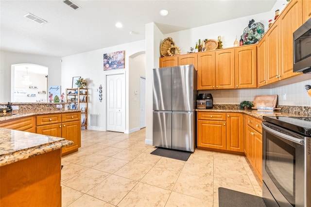 kitchen featuring backsplash, light stone counters, light tile patterned floors, and appliances with stainless steel finishes