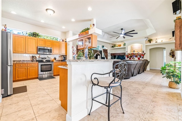 kitchen featuring a kitchen breakfast bar, kitchen peninsula, a wealth of natural light, and appliances with stainless steel finishes