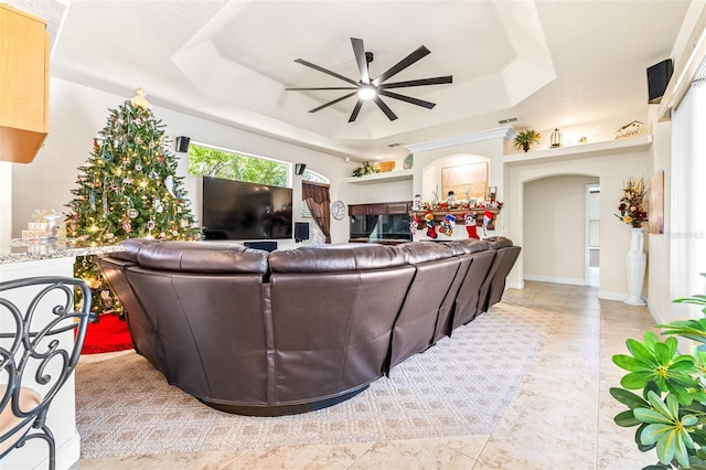 living room featuring ceiling fan and a raised ceiling