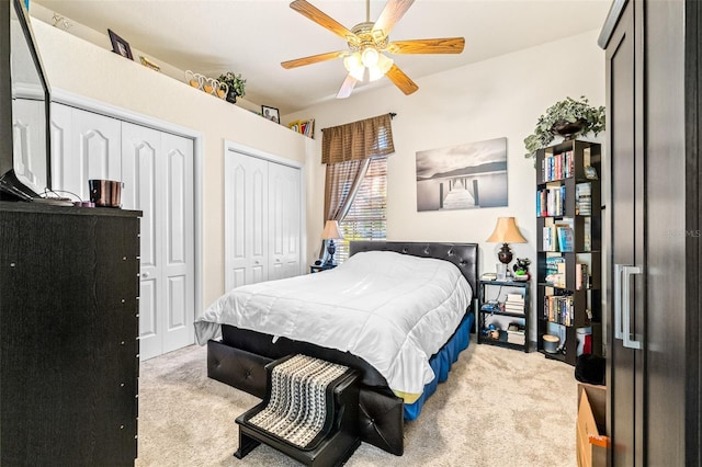 bedroom with light carpet, two closets, and ceiling fan