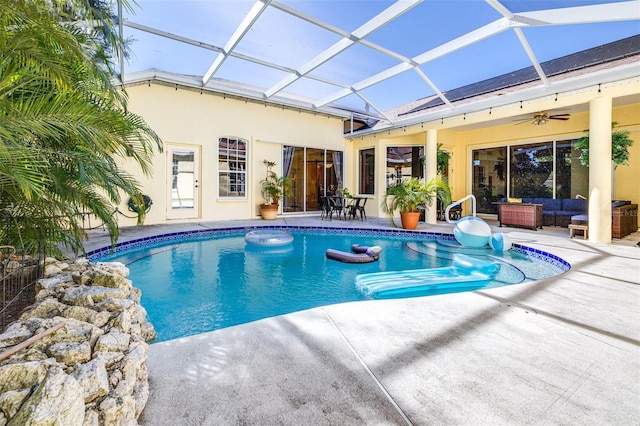 view of swimming pool featuring glass enclosure, ceiling fan, a patio, and an outdoor living space