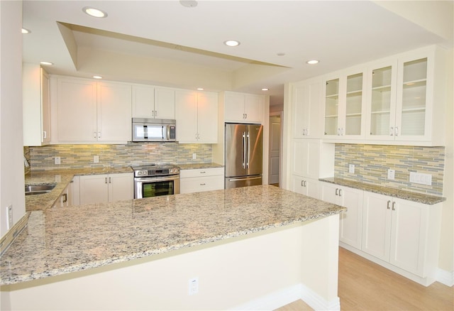 kitchen featuring white cabinetry, kitchen peninsula, stainless steel appliances, light stone counters, and sink