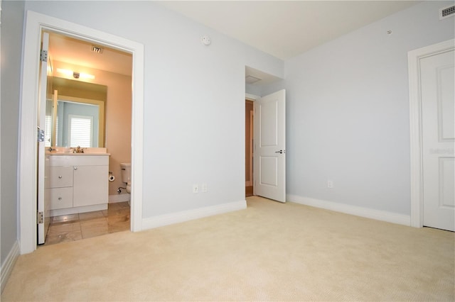 unfurnished bedroom featuring light colored carpet, connected bathroom, and sink