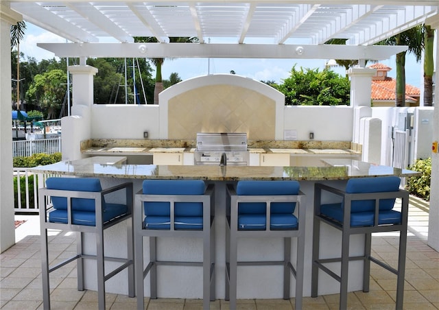 view of patio featuring exterior bar, an outdoor kitchen, and a pergola