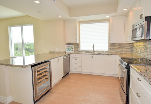 kitchen with white cabinetry, kitchen peninsula, stainless steel appliances, and wine cooler