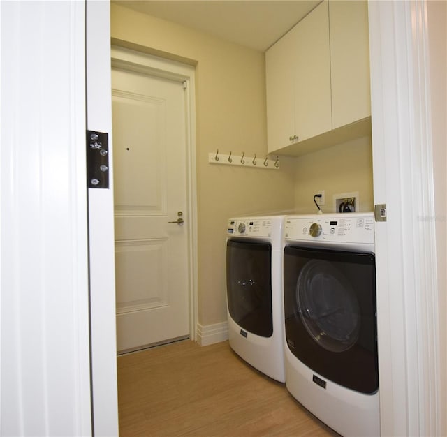 laundry room with cabinets, washer and clothes dryer, and light hardwood / wood-style floors