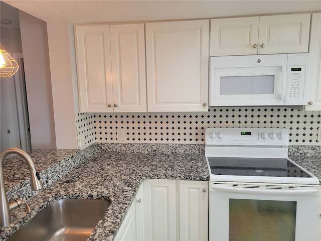 kitchen with white cabinetry, sink, dark stone countertops, white appliances, and decorative backsplash