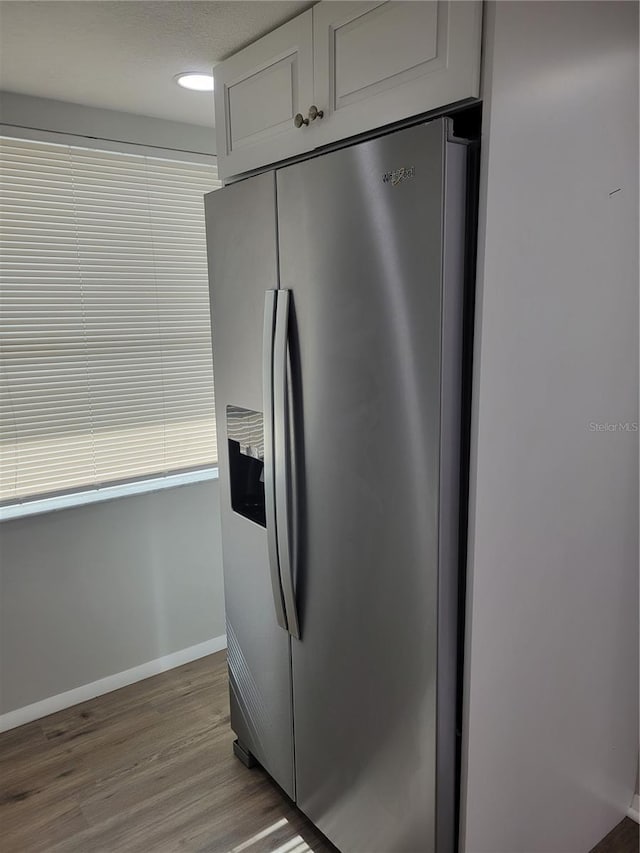 kitchen featuring white cabinets, stainless steel refrigerator with ice dispenser, and hardwood / wood-style flooring