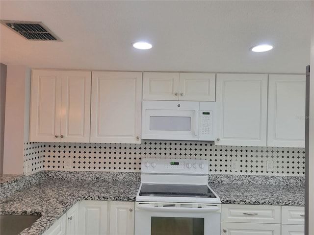 kitchen featuring tasteful backsplash, white cabinetry, dark stone counters, and white appliances