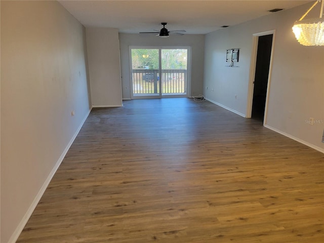 empty room with hardwood / wood-style floors and ceiling fan with notable chandelier