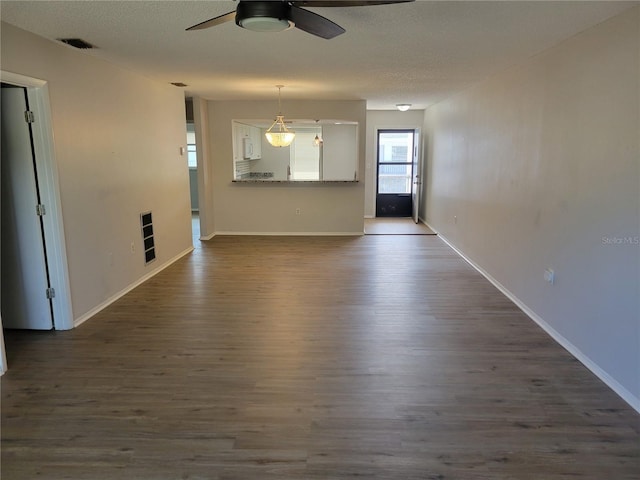 unfurnished living room featuring a textured ceiling, ceiling fan, and dark wood-type flooring