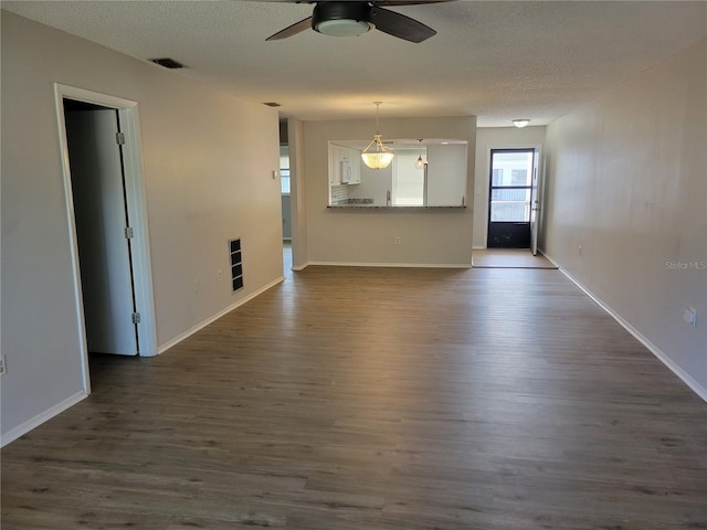 unfurnished living room featuring ceiling fan, dark hardwood / wood-style flooring, and a textured ceiling