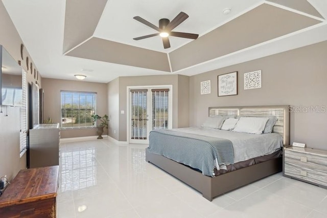 bedroom featuring tile patterned floors, ceiling fan, a tray ceiling, and access to outside