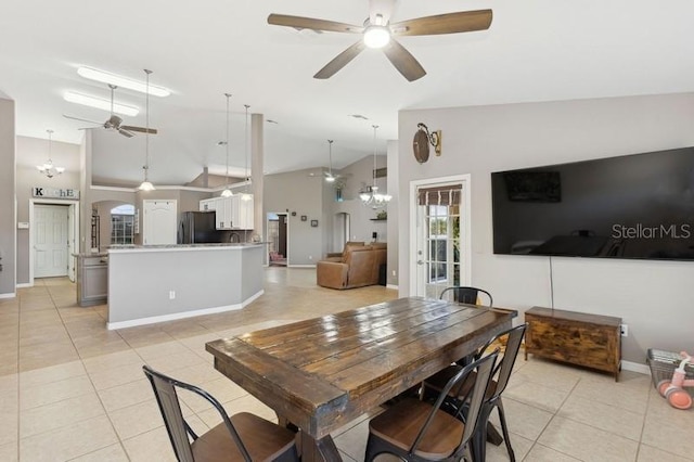 dining space with ceiling fan with notable chandelier, light tile patterned flooring, and high vaulted ceiling