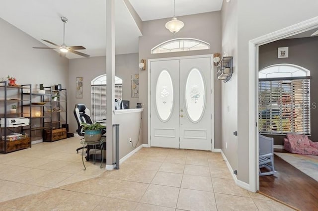 tiled entryway with ceiling fan and high vaulted ceiling