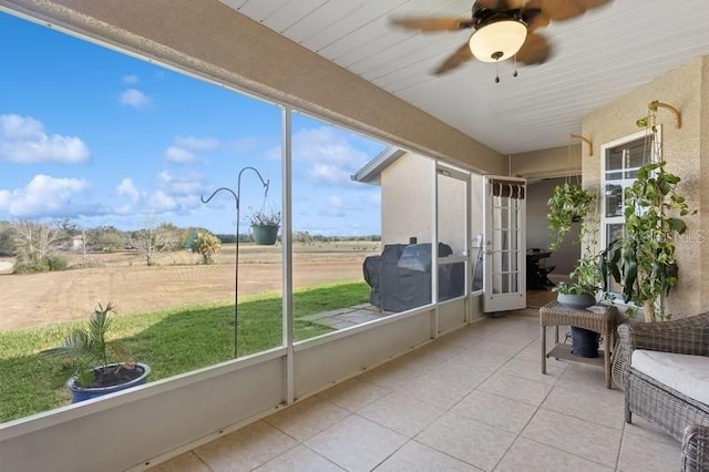 sunroom / solarium with ceiling fan and a rural view