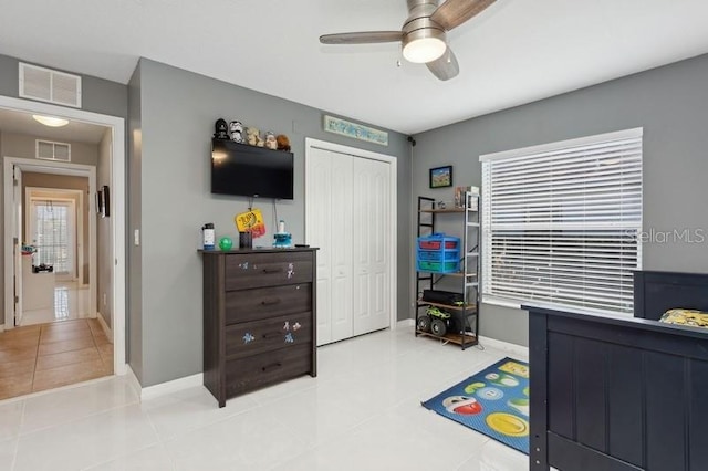 bedroom featuring ceiling fan, light tile patterned floors, and a closet