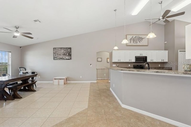 kitchen featuring light stone counters, vaulted ceiling, pendant lighting, white cabinets, and light tile patterned flooring