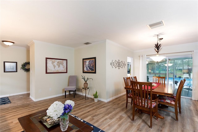 dining space with ornamental molding and hardwood / wood-style floors