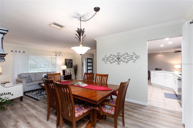 dining space featuring ornamental molding and light wood-type flooring