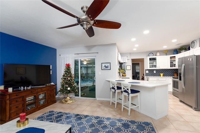 kitchen with a kitchen bar, appliances with stainless steel finishes, kitchen peninsula, white cabinets, and backsplash