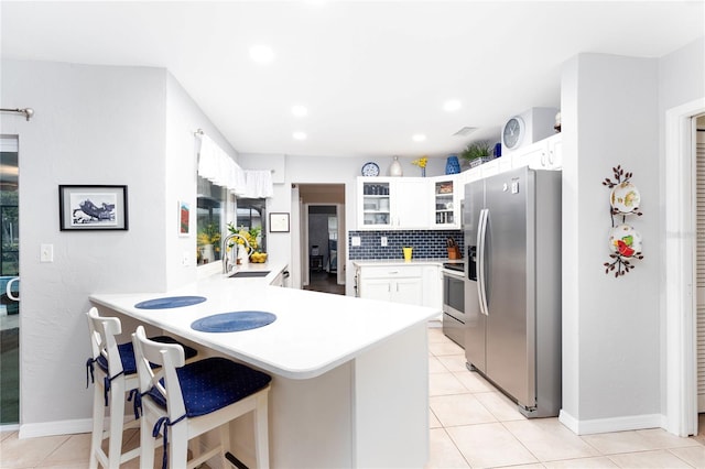 kitchen featuring sink, a breakfast bar area, white cabinetry, kitchen peninsula, and stainless steel appliances