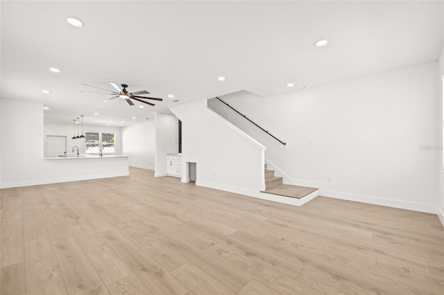 unfurnished living room with ceiling fan, sink, and light hardwood / wood-style flooring