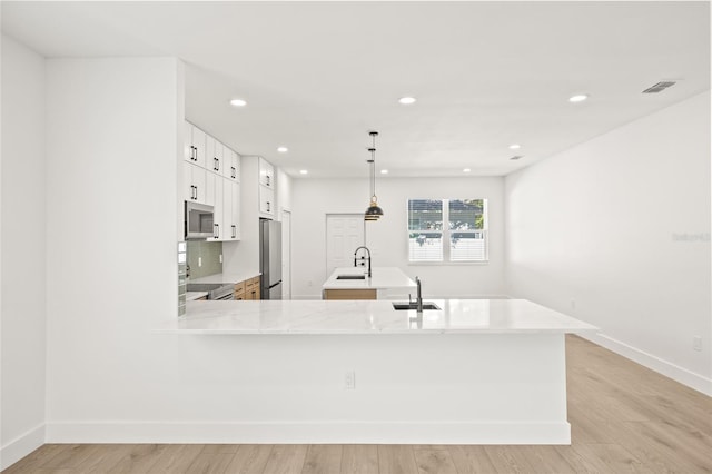 kitchen with sink, stainless steel appliances, kitchen peninsula, white cabinets, and light wood-type flooring