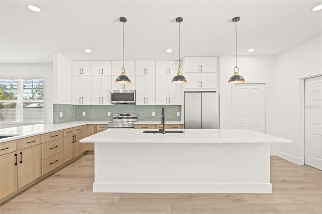 kitchen with sink, light brown cabinetry, an island with sink, and appliances with stainless steel finishes