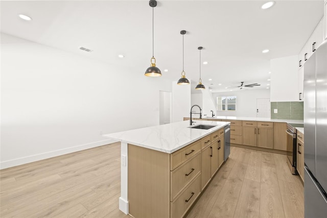 kitchen featuring ceiling fan, sink, an island with sink, and light hardwood / wood-style flooring