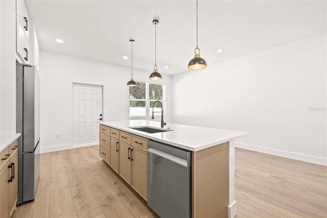 kitchen featuring sink, an island with sink, pendant lighting, light hardwood / wood-style floors, and appliances with stainless steel finishes