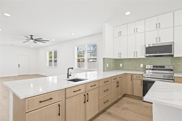 kitchen with sink, light wood-type flooring, white cabinetry, kitchen peninsula, and stainless steel appliances