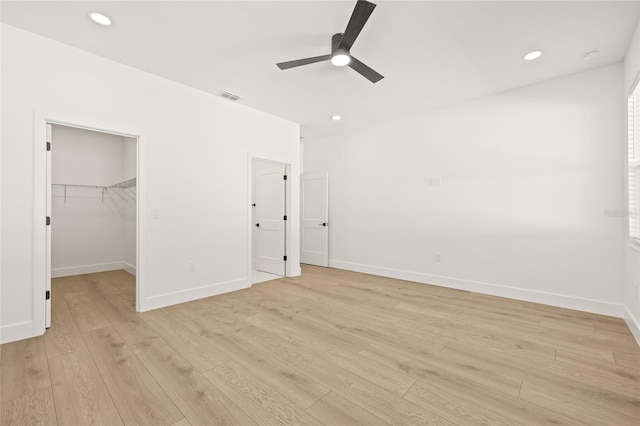 unfurnished bedroom featuring a closet, light hardwood / wood-style flooring, a spacious closet, and ceiling fan