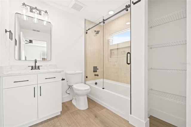 full bathroom featuring toilet, hardwood / wood-style floors, vanity, and combined bath / shower with glass door