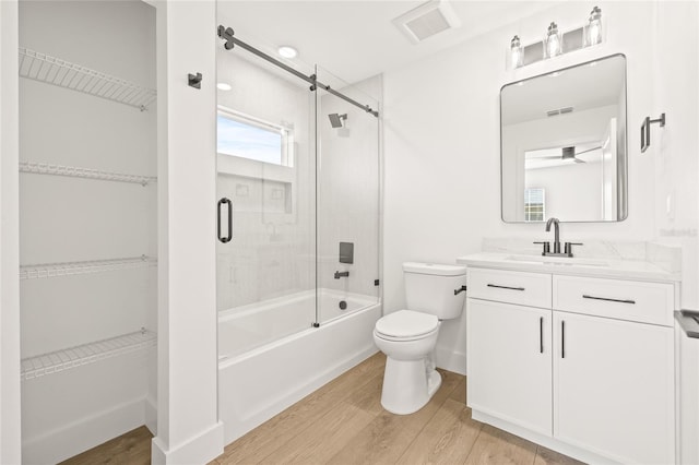 full bathroom featuring shower / bath combination with glass door, wood-type flooring, vanity, and toilet