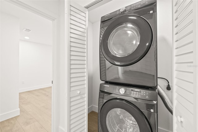 laundry room featuring light hardwood / wood-style flooring and stacked washer / drying machine