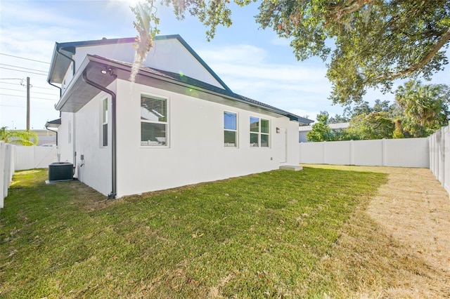 rear view of house with central air condition unit and a yard