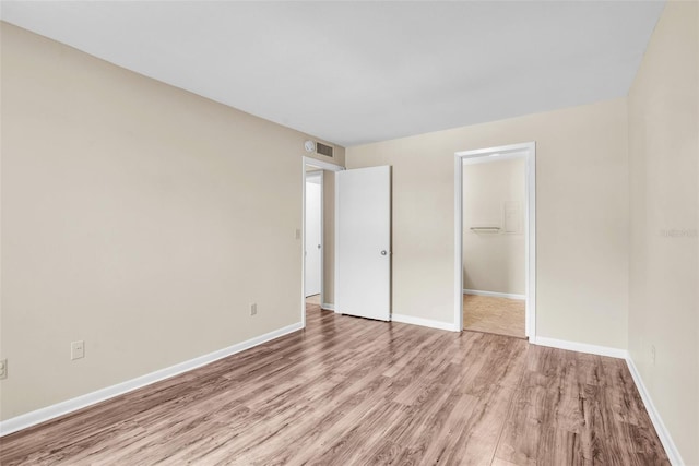 unfurnished bedroom featuring a walk in closet, a closet, and light hardwood / wood-style flooring