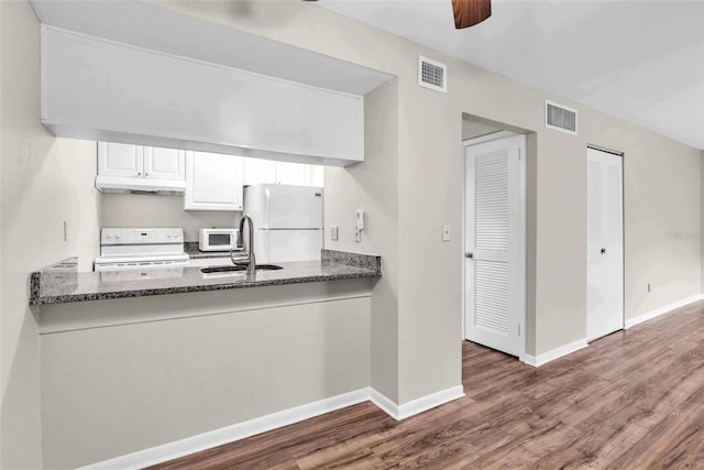 kitchen featuring white cabinetry, sink, dark hardwood / wood-style flooring, dark stone countertops, and white appliances