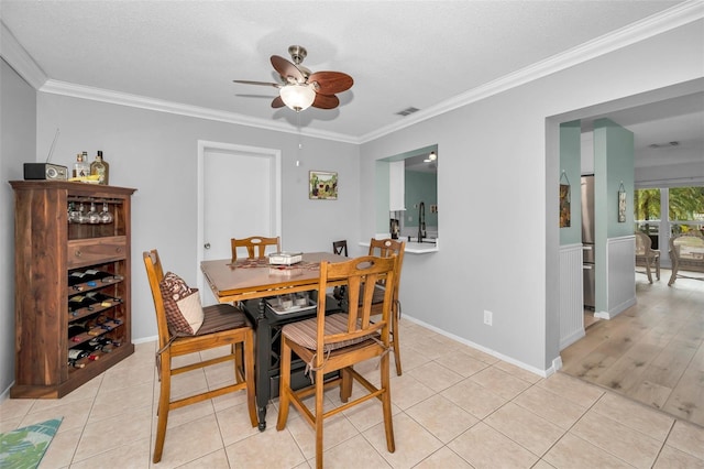 tiled dining space with sink, ornamental molding, a textured ceiling, and ceiling fan