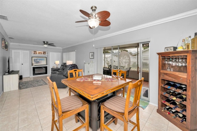 tiled dining room featuring crown molding, ceiling fan, and a textured ceiling