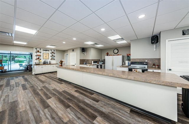 kitchen featuring dark wood-type flooring, backsplash, white refrigerator, black electric range, and white cabinets