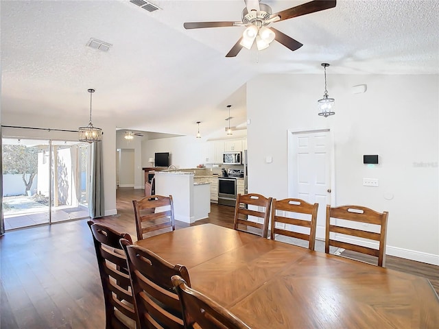 dining space with ceiling fan with notable chandelier, a textured ceiling, dark hardwood / wood-style floors, and vaulted ceiling