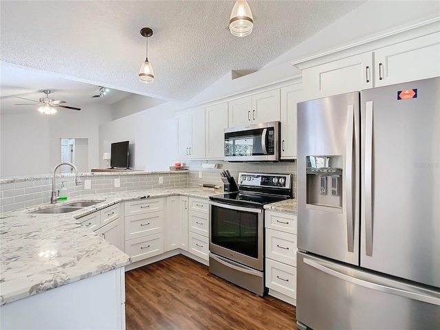 kitchen with sink, vaulted ceiling, a textured ceiling, appliances with stainless steel finishes, and white cabinetry