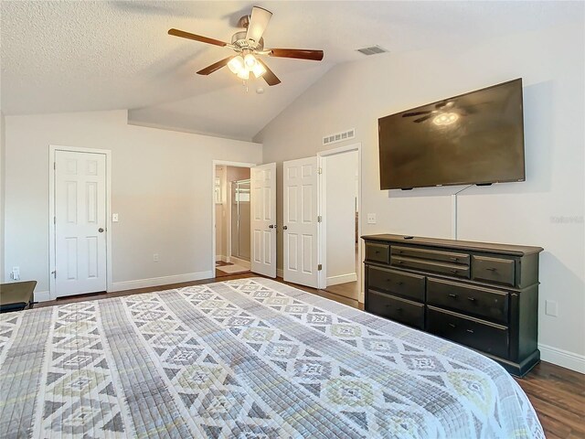 bedroom with a textured ceiling, ceiling fan, dark wood-type flooring, and vaulted ceiling