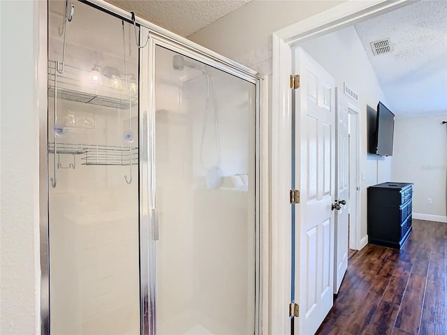 bathroom featuring hardwood / wood-style floors, a textured ceiling, vaulted ceiling, and an enclosed shower