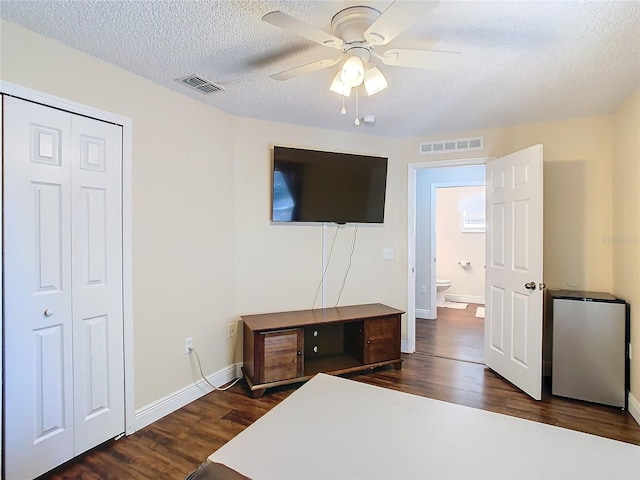 bedroom with ceiling fan, a closet, dark wood-type flooring, and a textured ceiling