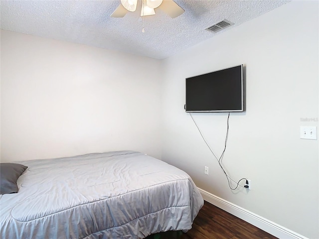 bedroom featuring a textured ceiling, dark hardwood / wood-style floors, and ceiling fan