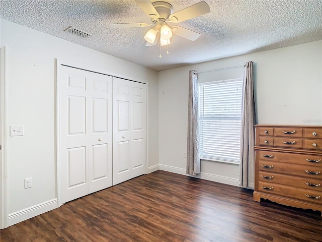 unfurnished bedroom featuring a closet, ceiling fan, dark hardwood / wood-style flooring, and a textured ceiling